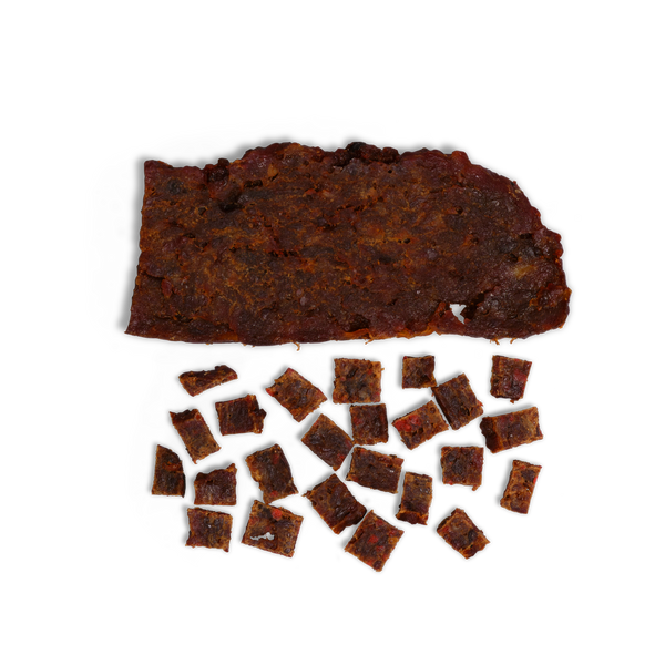 A large piece of dark brown jerky rests atop several small, square Beef and Pumpkin dog treats—ideal all-natural training treats—on a white background.